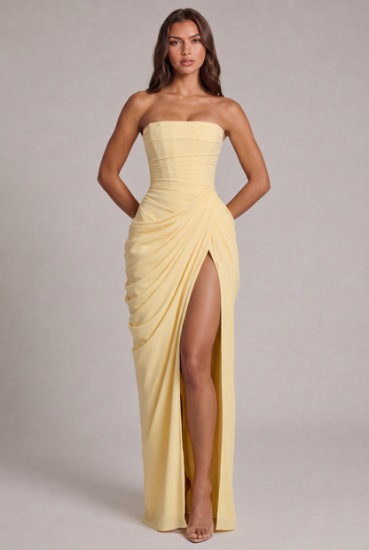 Model trägt das zartgelbe trägerlose Chiffonkleid in der Frontansicht, Hände hinter dem Rücken, mit hohem Beinschlitz 1