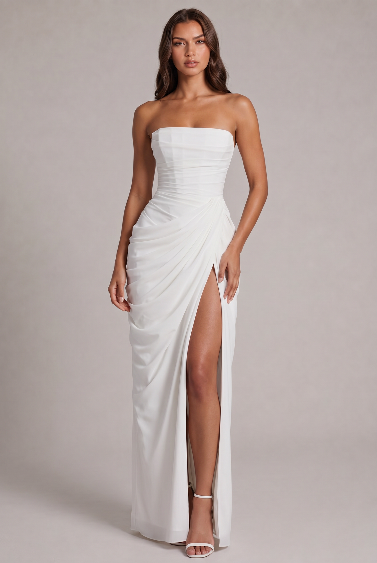 Model trägt das weiße trägerlose Maxikleid frontal, drapierter Rock, hoher Beinschlitz, weiße Riemchensandalen 17