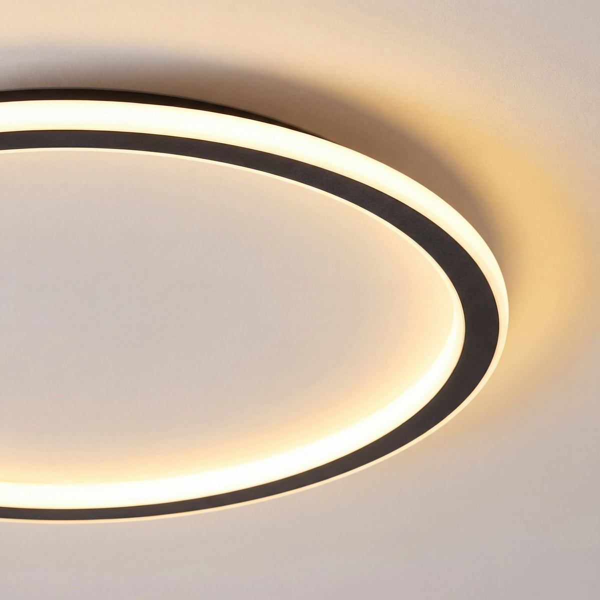 Nahaufnahme eines Ausschnitts der Leuchte mit schwarzem Metallring und gleichmäßig leuchtendem, warmem Lichtband. 2