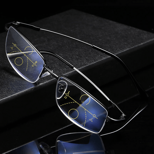 Schwarze Gleitsichtbrille mit gelben Zonenmarkierungen auf den Gläsern, schräg auf einem dunklen Block abgelegt und gespiegelt. 5