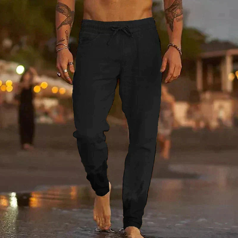 Mann in schwarzen Jogginghosen am Strand bei Sonnenuntergang, Freizeitmode, Herrenbekleidung.