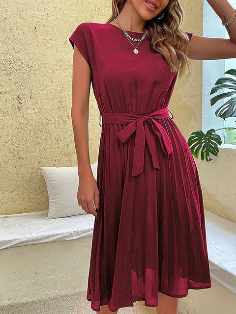 Frau in elegantem, rotem, plissiertem Midi-Kleid mit Gürtel und kurzen Ärmeln.