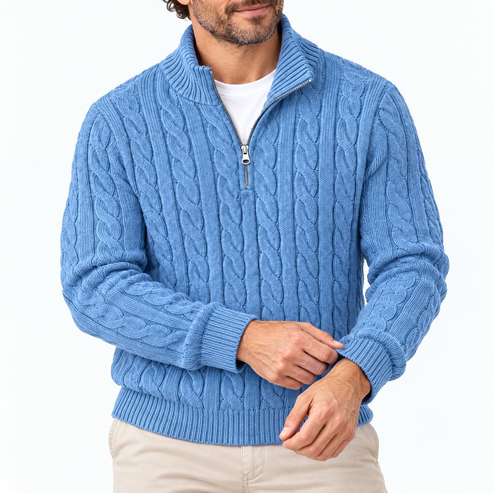 Mann in hellblauem Zopfstrick-Pullover mit halbem Reißverschluss, Nahaufnahme von Oberkörper, Händen und gerippter Manschette, beige Hose. 1