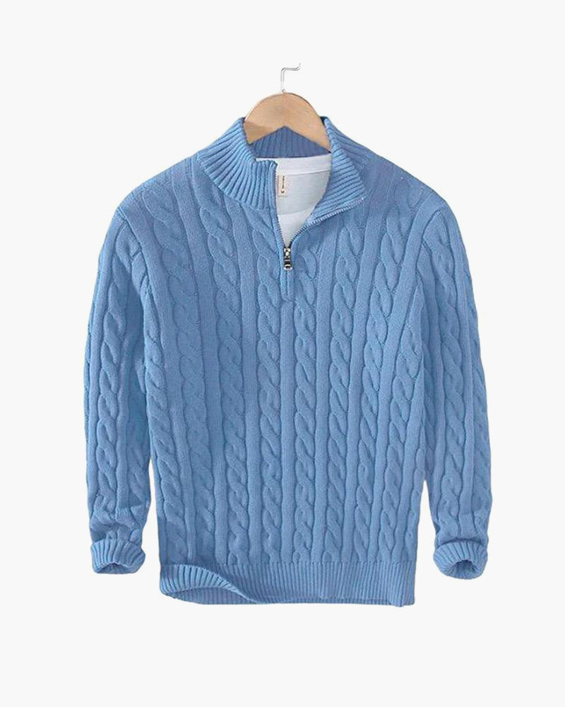 Hellblauer Zopfstrick-Pullover mit Stehkragen und kurzem Reißverschluss auf Holzbügel hängend, Produktfoto vor weißem Hintergrund. 17