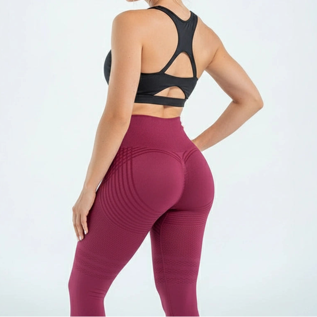 Rückansicht der beerenroten Leggings am Model mit schwarzem Sport-BH, geformtes Gesäß und gebogene Streifen am Bund. 6