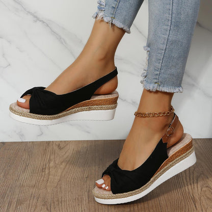 Schwarze Damen-Sandalen mit Keilabsatz, bequem, Sommermode, Jeanshintergrund.