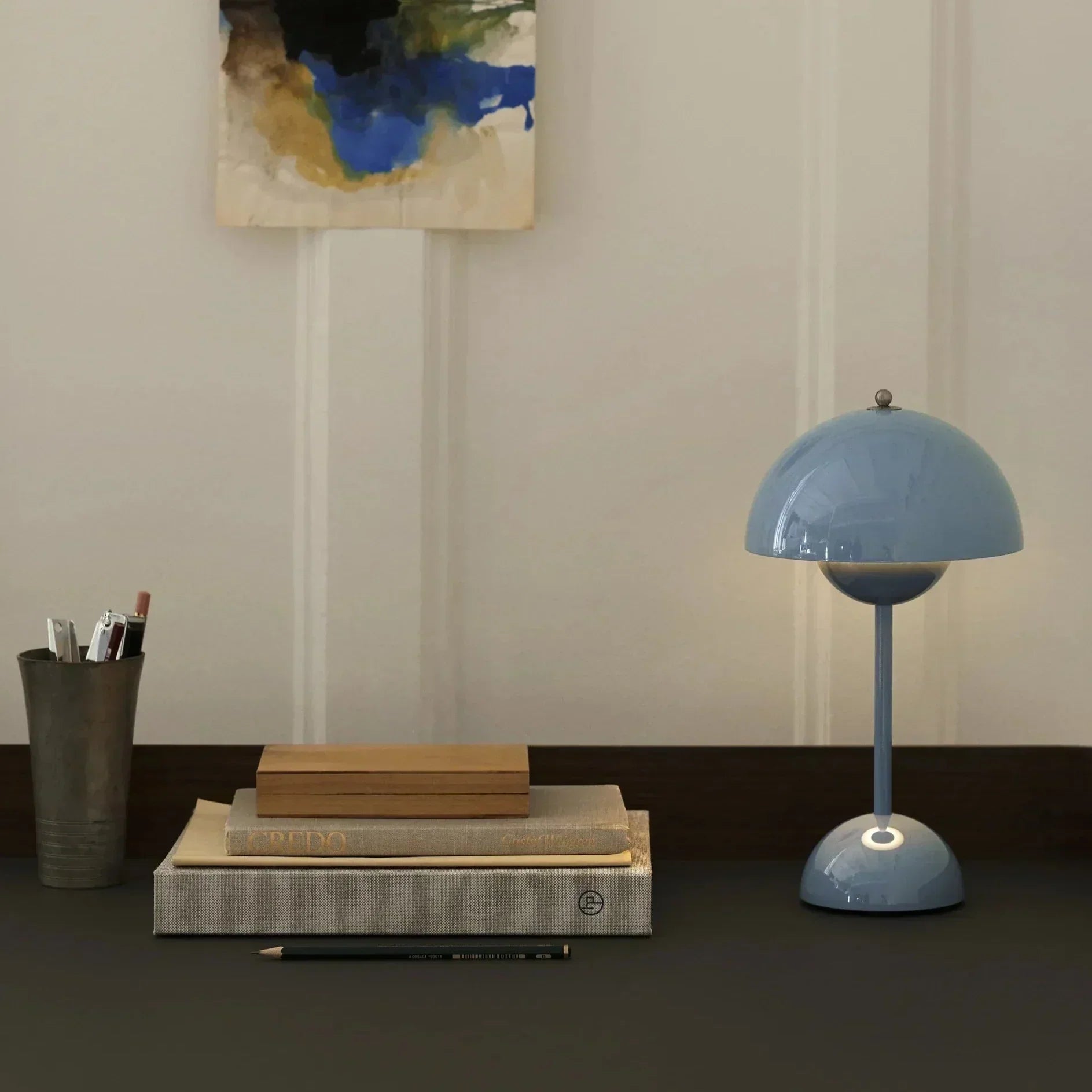 Blaue Tischlampe aus Metall auf Schreibtisch mit Büchern und Stiften, modernes Design.