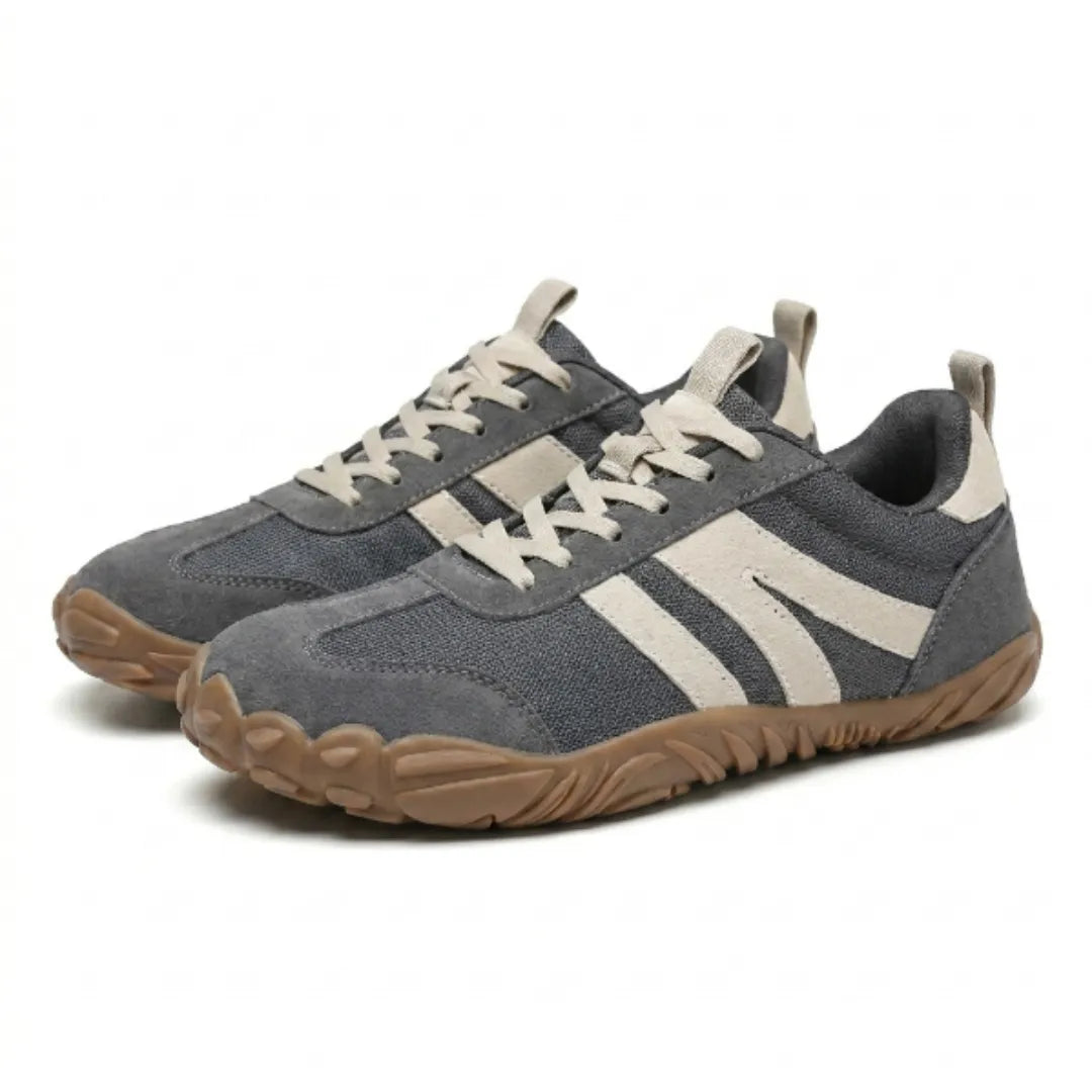 Graues Schuhpaar mit beigen Streifen und heller Schnürung in schräger Ansicht, zeigt Seite, Vorderkappe und braune Sohle. 7