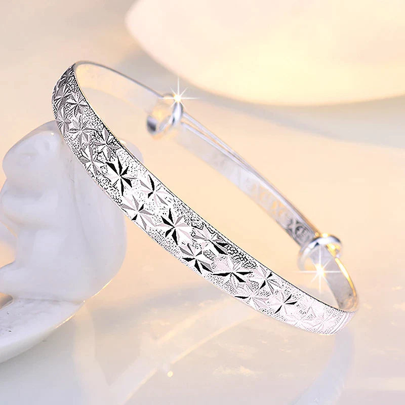 Silberarmreif mit Sternenmuster, glänzend, elegantes Schmuckstück für Damen.