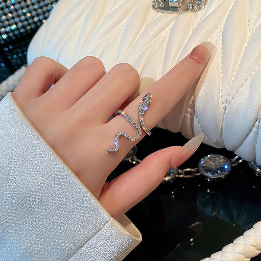 Silberner Schlangenring mit Strasssteinen auf Finger, elegante Damenmode, Nahaufnahme.