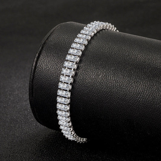 Silbernes Tennisarmband mit rechteckigen Zirkonia-Steinen auf schwarzem Hintergrund.