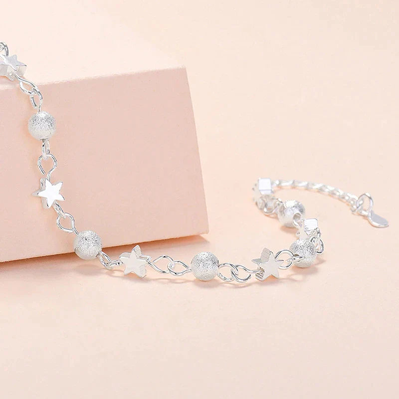 Silbernes Armband mit Stern- und Kugelanhängern, elegantes Schmuckdesign für Damen.