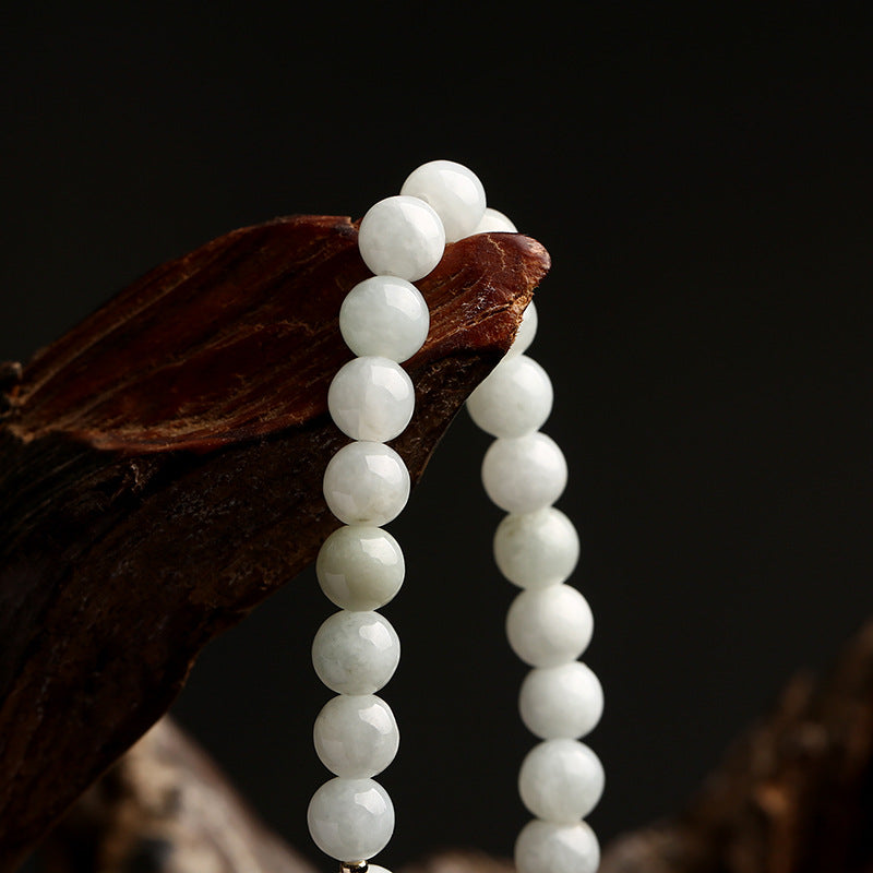 Weiße Jade-Perlenkette auf Holz, eleganter Schmuck, Naturstein, Nahaufnahme.