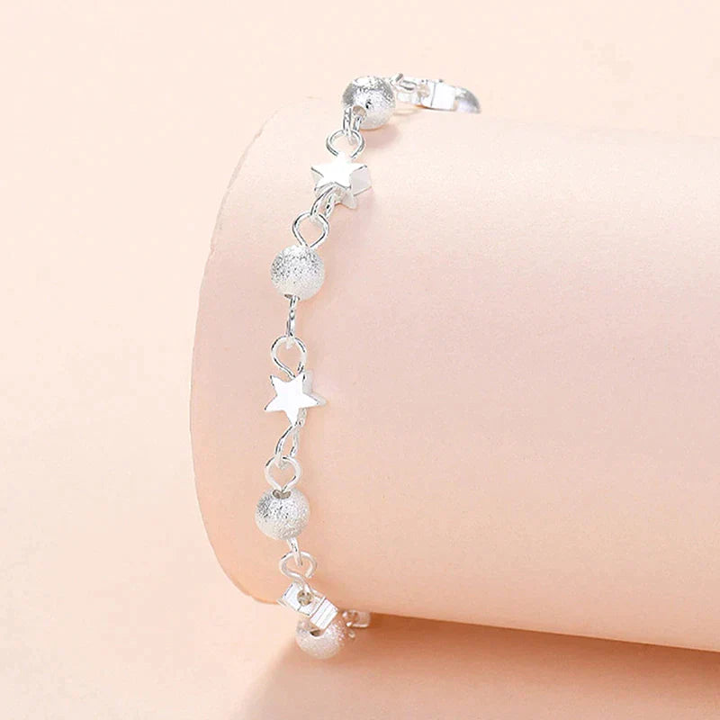 Silberarmband mit Stern- und Kugelanhängern, Damen-Schmuck, elegantes Design.