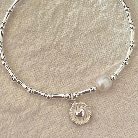 Silberarmband mit Perle und Herzanhänger, elegantes Schmuckdesign, Damenaccessoire.