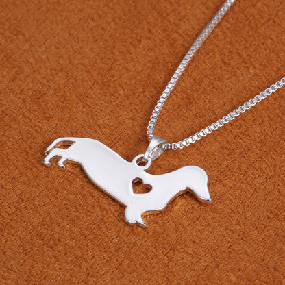 Silberne Dackel-Halskette mit Herzanhänger auf braunem Hintergrund, Schmuck für Hundeliebhaber.