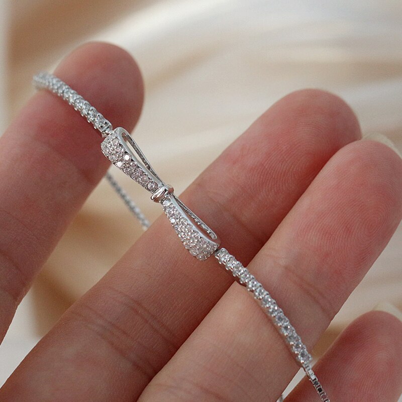 Silbernes Armband mit Schleife, Zirkonia-Steinen, elegantes Schmuckdesign, Nahaufnahme.