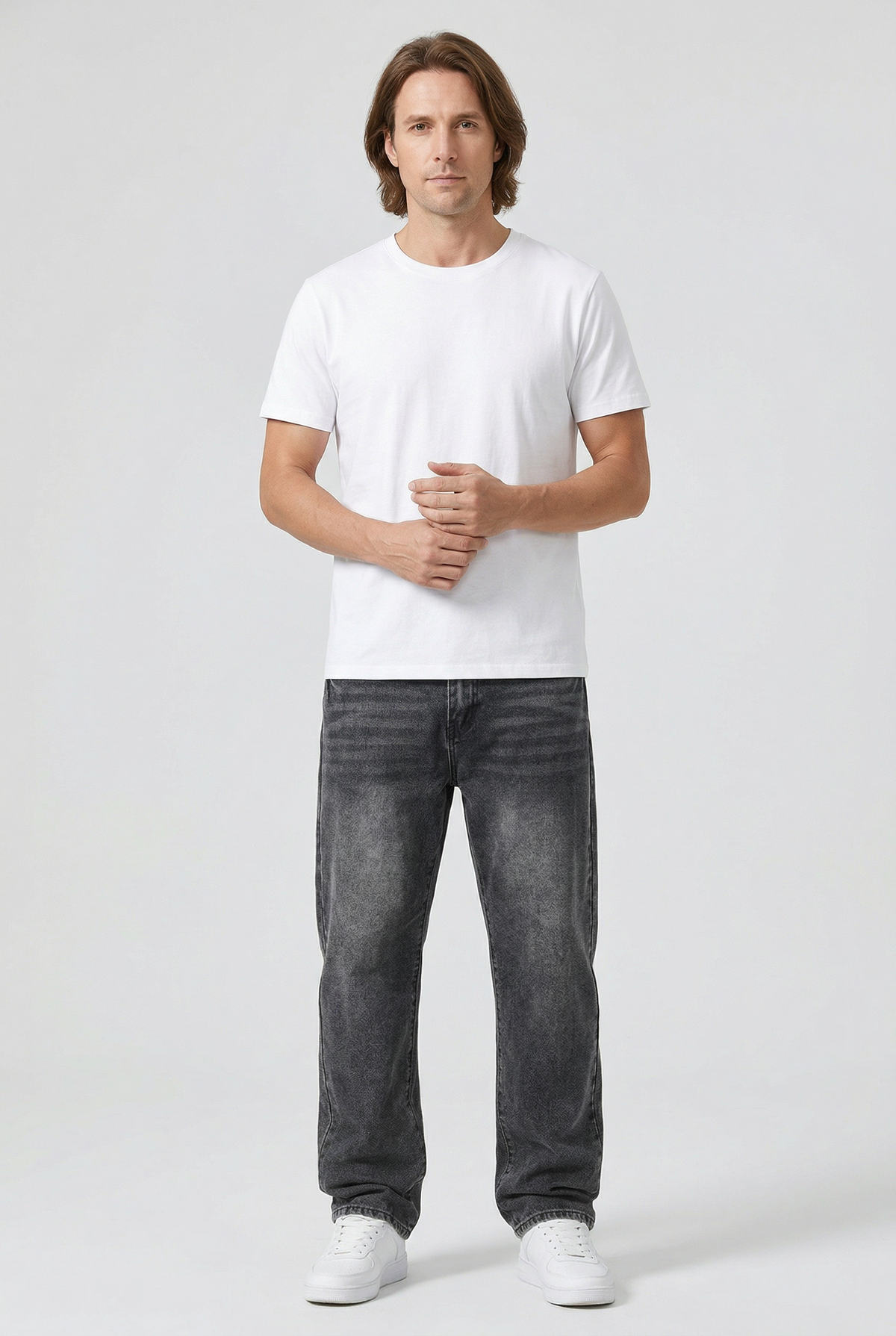 Ganzkörperaufnahme eines Models in grauer Jeans mit geradem Bein, weißem T-Shirt und Sneakern vor hellem Hintergrund 2