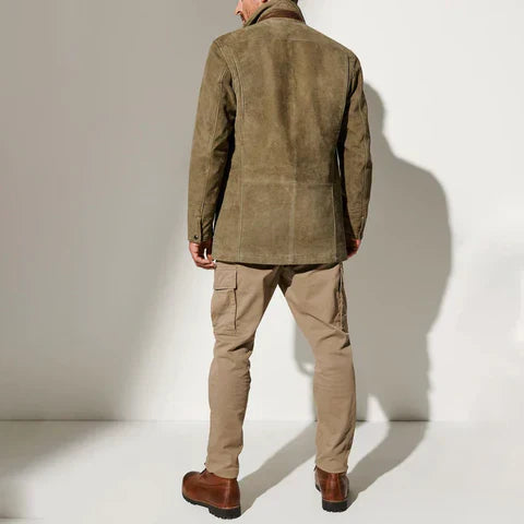 Rückansicht der olivgrünen Jacke am Model, kombiniert mit beiger Cargohose und braunen Lederstiefeln im hellen Studio. 3