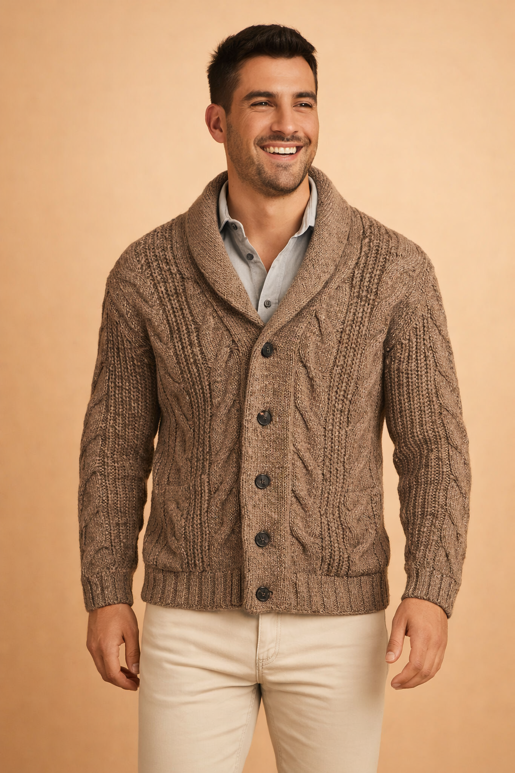 Nahaufnahme der braun melierten Strickjacke mit grobem Zopfmuster, Schalkragen, Knopfleiste und aufgesetzten Taschen, getragen über hellblauem Hemd. 3