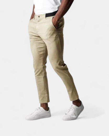 Die Hose in Beige, getragen von einem Model mit weißem Shirt, Hände in den Seitentaschen 3