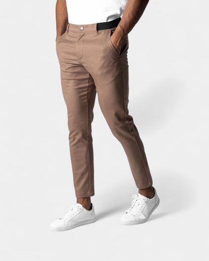 Die Hose in Braunbeige am Model, mit Knopfverschluss, schwarzem Elastikbund und weißen Sneakern 5