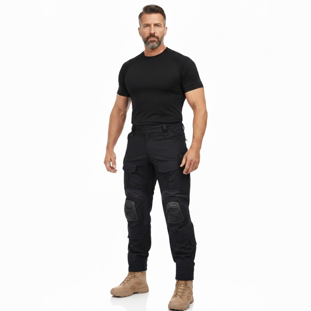 Bärtiger Model-Mann in schwarzem Shirt und schwarzer Hose mit Knieschonern, beigen Stiefeln, Ganzkörperansicht von vorn. 7