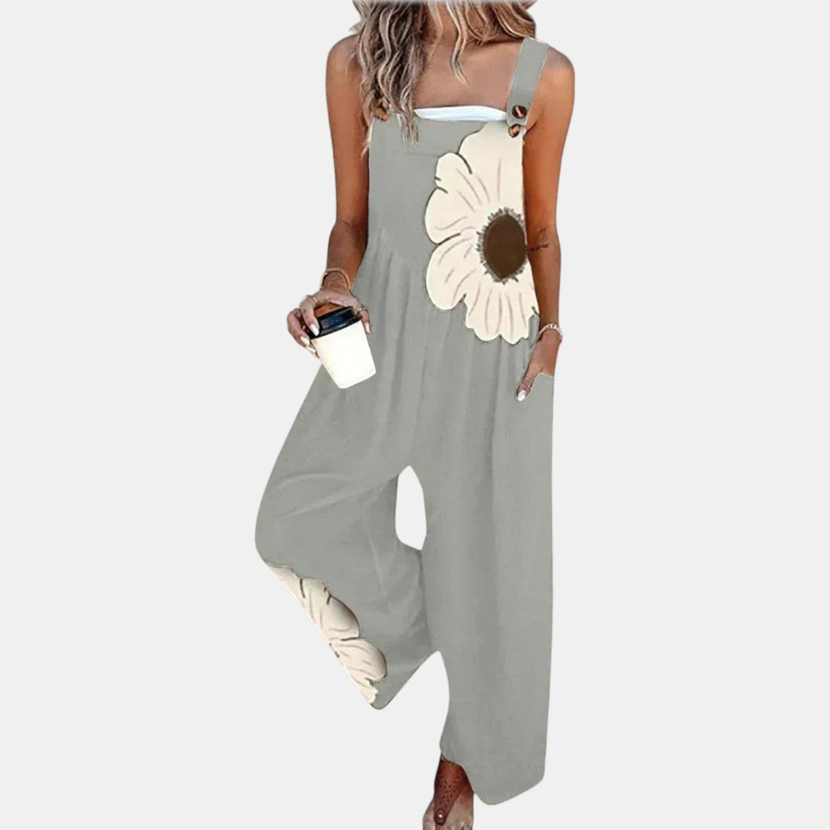 Graue Latzhose mit cremefarbener Blüte auf Brust und Hosenbein, Model hält Kaffeebecher 11