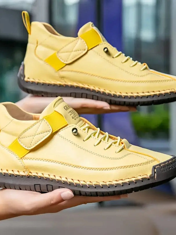 Gelbe Sneaker mit dunkler Sohle, auf zwei Händen präsentiert, mit gelbem Riemen 15