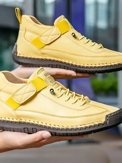 Gelbe Sneaker mit dunkler Sohle, auf zwei Händen präsentiert, mit gelbem Riemen 15