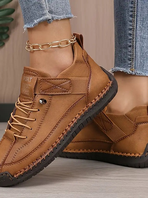 Braune Sneaker am Fuß einer Frau, Detailansicht von Riemen, Schnürung und genähtem Sohlenrand 7