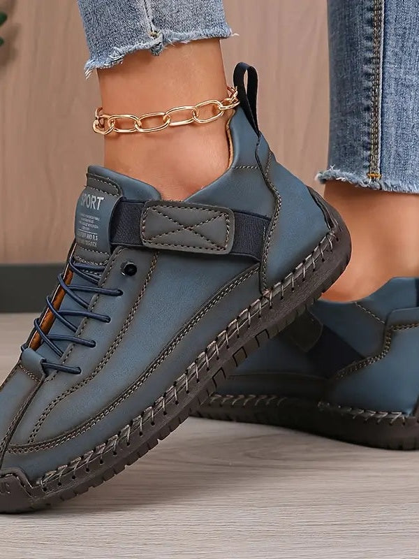 Blaugraue Sneaker am Fuß einer Frau, Nahaufnahme von elastischem Riemen und dunkler Sohle 9