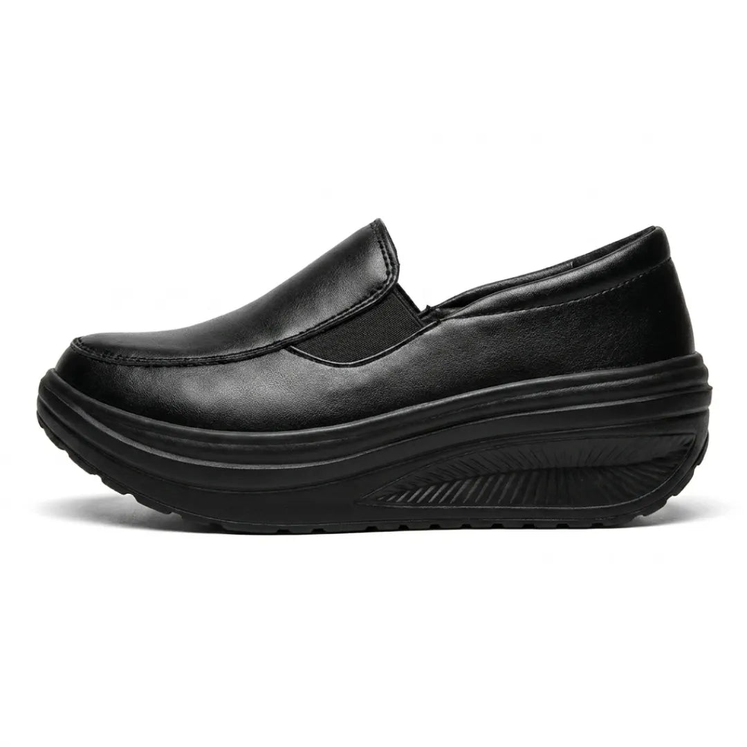 Schwarzer Slipper mit Keilsohle in der Seitenansicht, seitlicher Gummizug und profilierte Sohle sichtbar 1