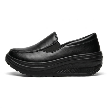 Schwarzer Slipper mit Keilsohle in der Seitenansicht, seitlicher Gummizug und profilierte Sohle sichtbar 1