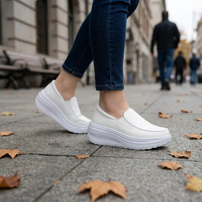 Weiße Slipper an den Füßen einer Frau in Jeans auf einem Gehweg mit Herbstlaub 11