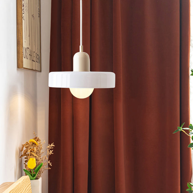 Moderne weiße Glas-Pendelleuchte vor braunem Vorhang im Wohnzimmer.
