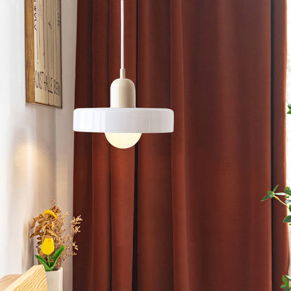 Moderne weiße Glas-Pendelleuchte vor braunem Vorhang im Wohnzimmer.