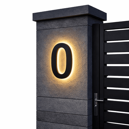 Schwarze Ziffer 0 mit warmem Hintergrundlicht an einem grauen Steinpfeiler vor schwarzem Lamellentor, freigestellt. 6