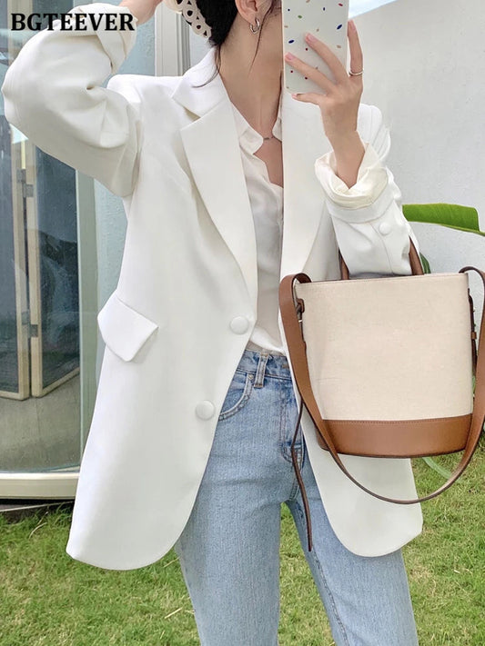 Frau in weißem Blazer, Jeans, mit beiger Umhängetasche, Herbstmode, eleganter Damenstil.