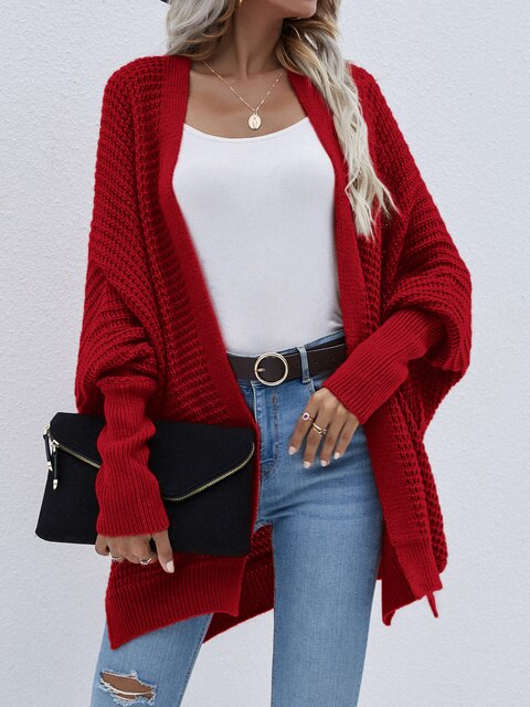 Frau trägt roter Strick-Cardigan, weißes Top, blaue Jeans, schwarze Clutch, Herbstmode.