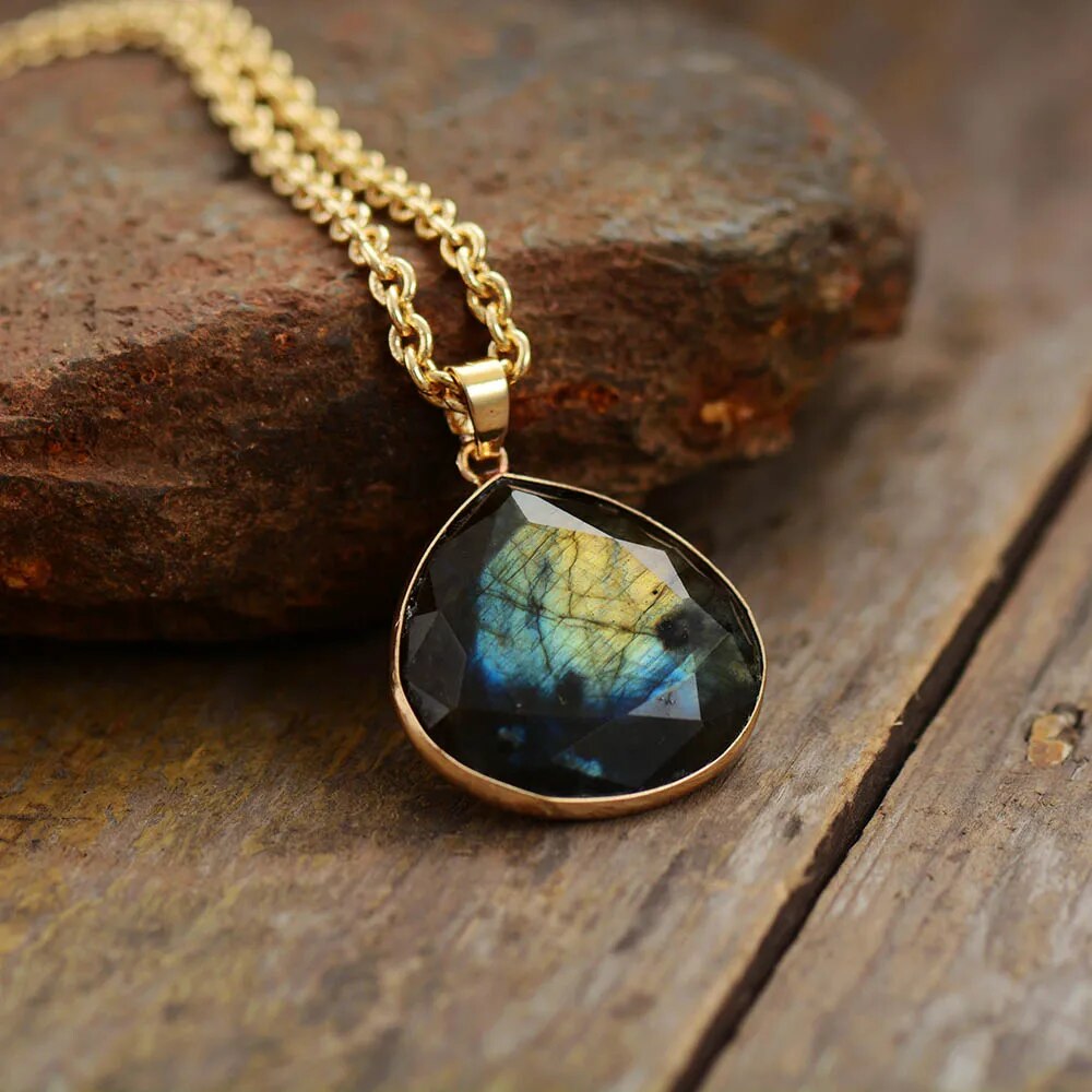 Labradorit Tropfenanhänger, goldene Kette, natürliche Edelsteine, Schmuck, rustikaler Hintergrund.