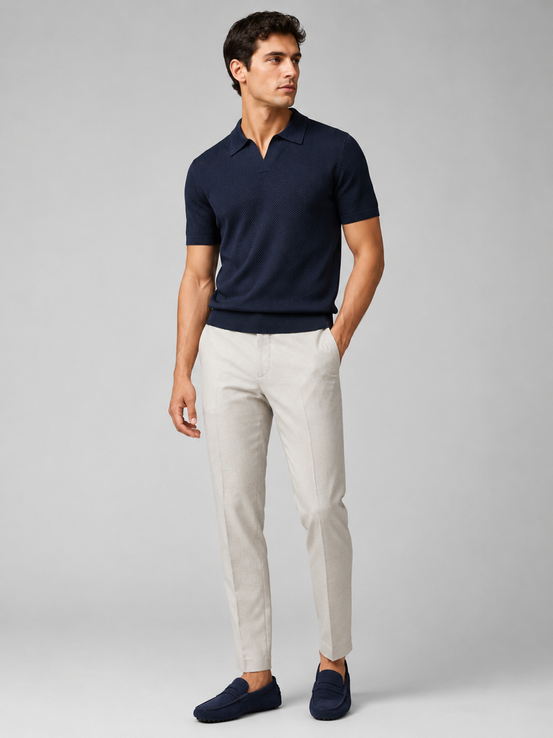 Ganzkörperansicht des Models im dunkelblauen Strickpolo mit hellgrauer Hose und blauen Wildleder-Mokassins 37