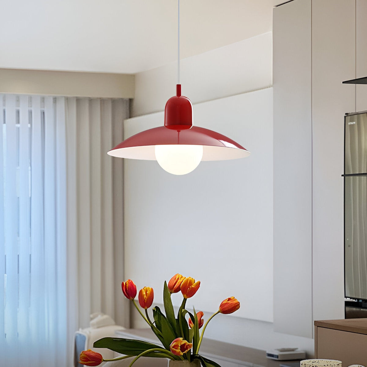 Rote Pendelleuchte mit flachem Schirm und Milchglaskugel im Wohnraum, davor Tulpen in einer Vase 1