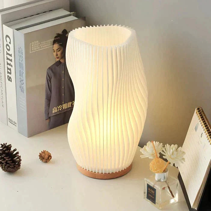 Moderne weiße Tischlampe aus Papier, wellenförmig, auf Holzsockel, ideal für Wohnzimmerbeleuchtung.