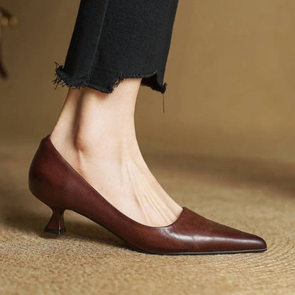 Seitenansicht eines dunkelbraunen Pumps am Fuß, mit schmalem Absatz und spitzer Kappe, dazu schwarze Hose 19