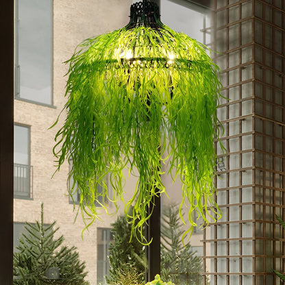 Leuchte mit langen, grasartigen grünen Kunstpflanzen vor Fenster und Holzgitter, die Glühbirnen schimmern durch 2