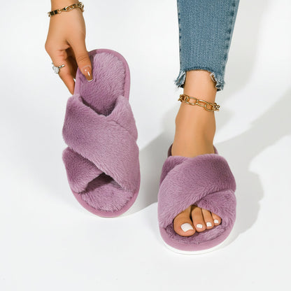 Violette Plüsch-Pantoffeln mit gekreuzten Riemen, ein Schuh in der Hand gehalten, dazu eine Jeans mit Fransensaum. 8