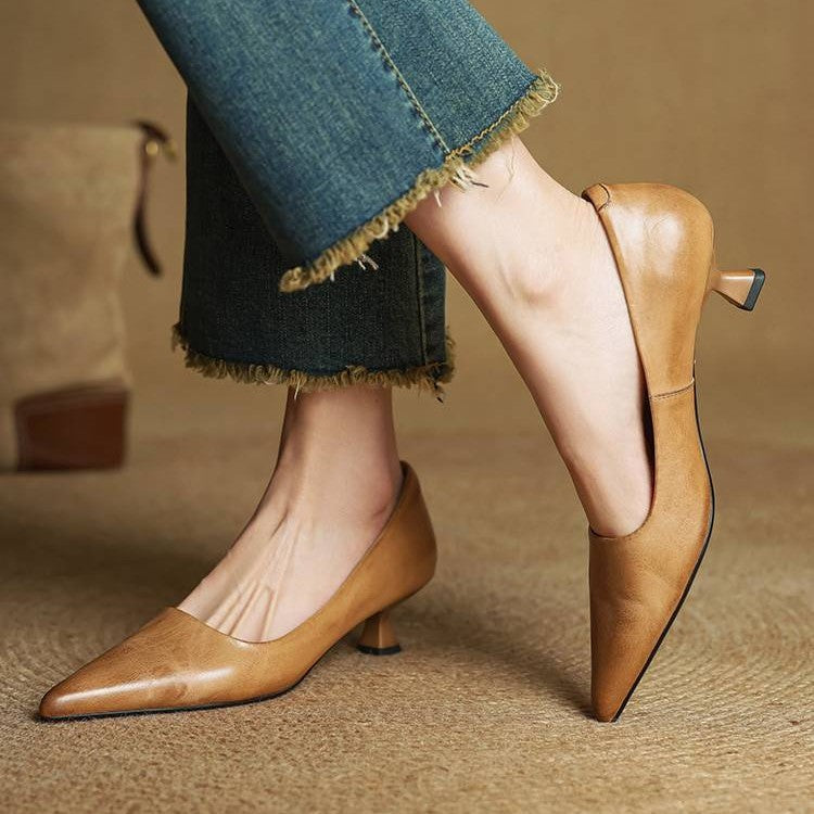 Model in karamellbraunen Pumps und ausgefransten Jeans, ein Fuß angehoben, sodass Absatz und Rückseite sichtbar sind 3