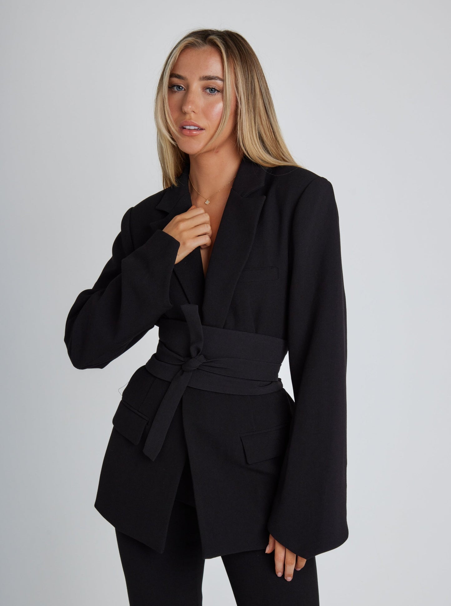 Frau in schwarzem Blazer mit Gürtel, modisch, elegant, Damenmode, Business-Outfit, Studioaufnahme.