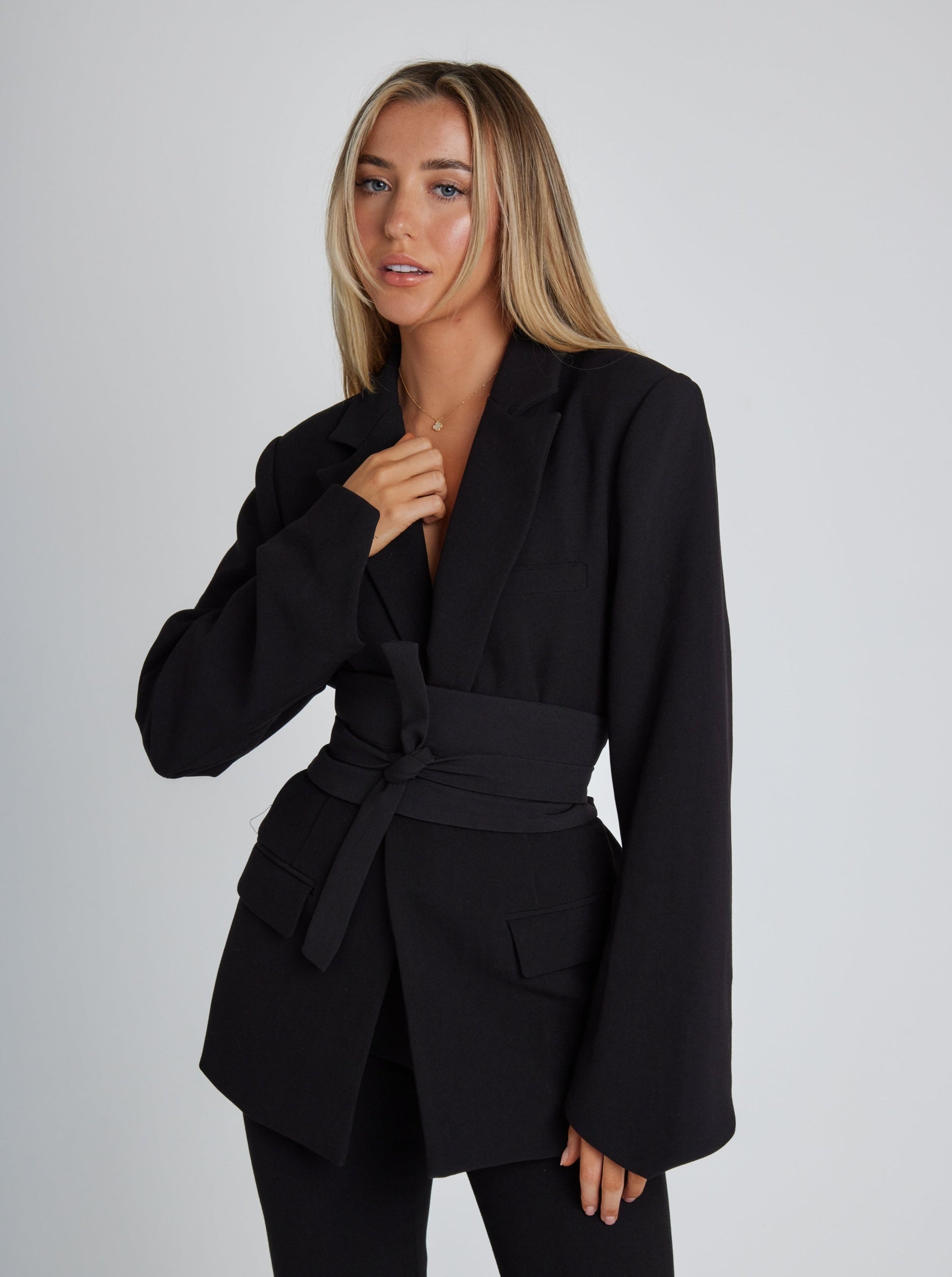 Frau in schwarzem Blazer mit Gürtel, modisch, elegant, Damenmode, Business-Outfit, Studioaufnahme.